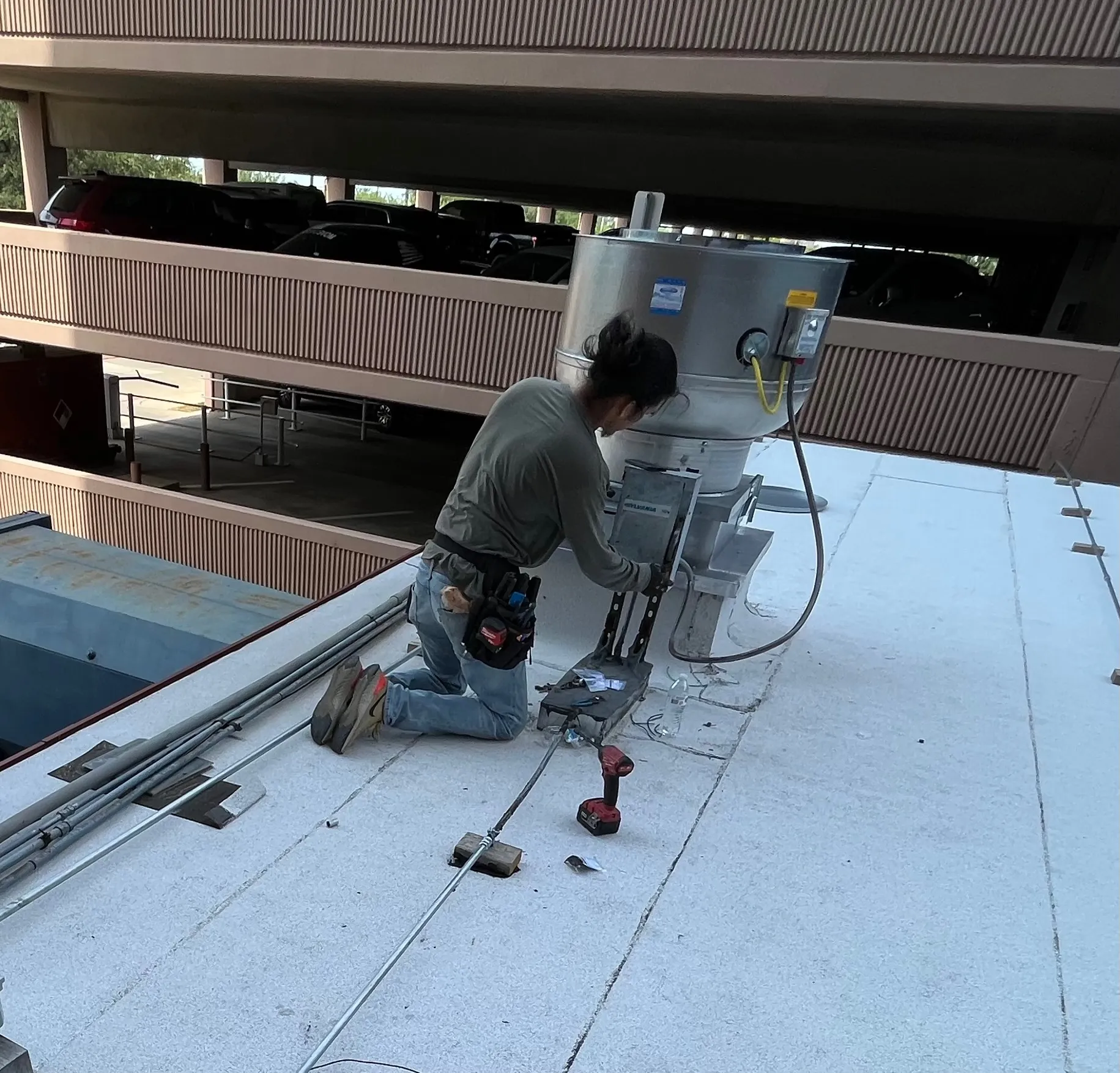 Technician working on commercial rooftop exhaust equipment